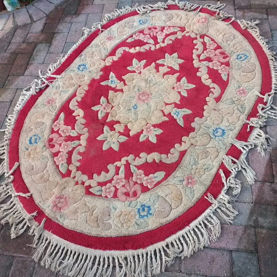 Round floral wool mat before cleaning, dulled with age